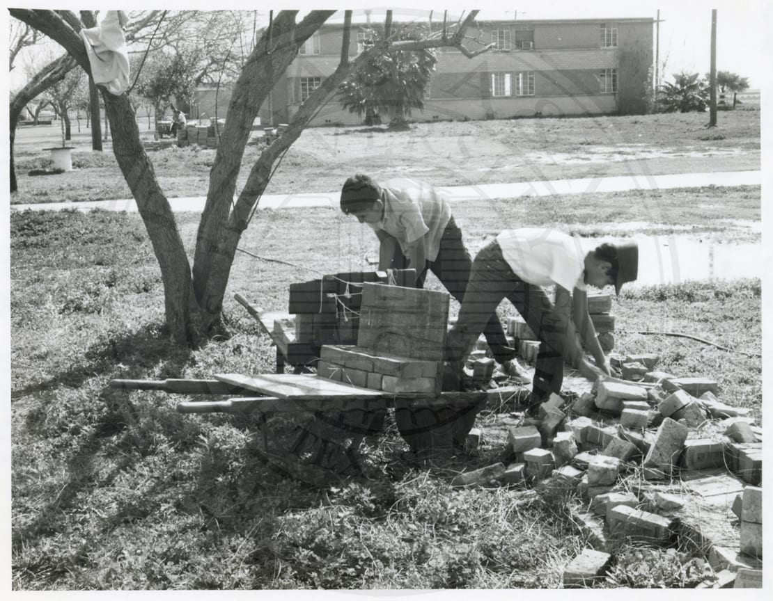 Two boys loading bricks on a cart, 1965–66.