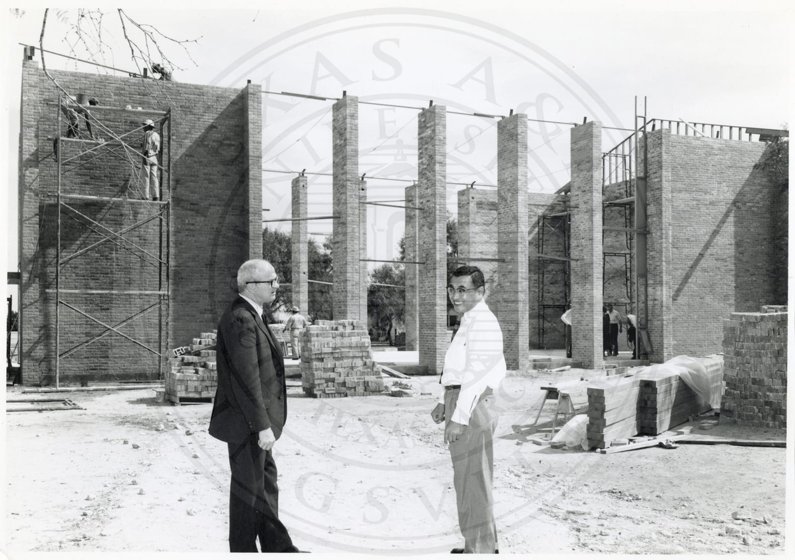 Two men in spectacles at a building going up.