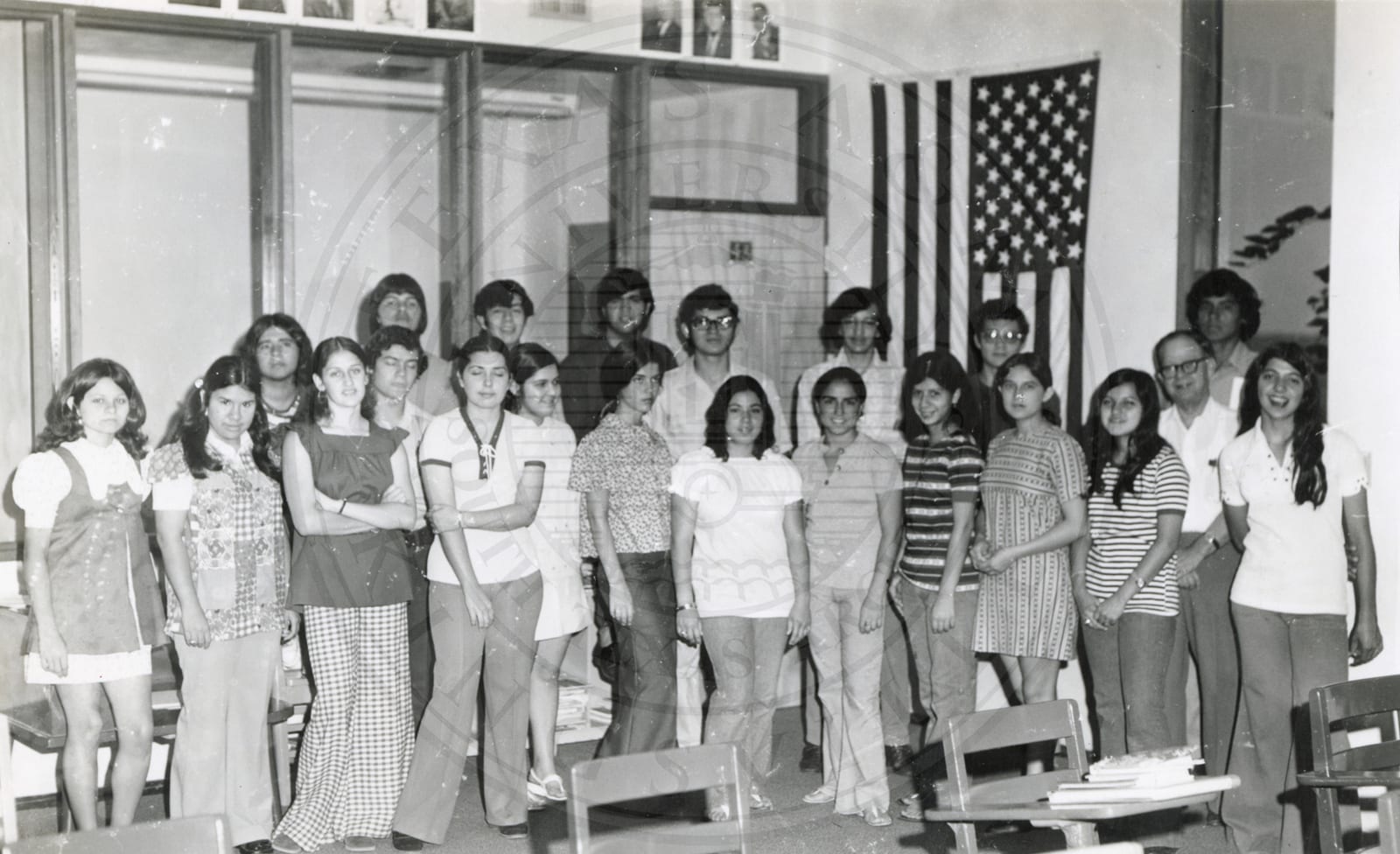 A class with its teacher, the flag on the wall.