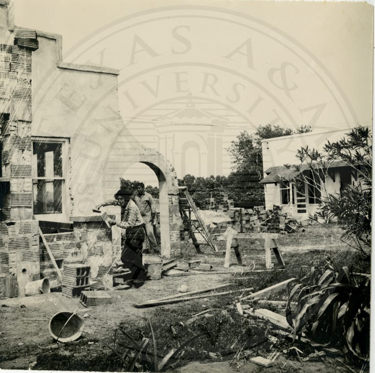 Students building a house on the Tex-Mex campus; to the right, one already built.