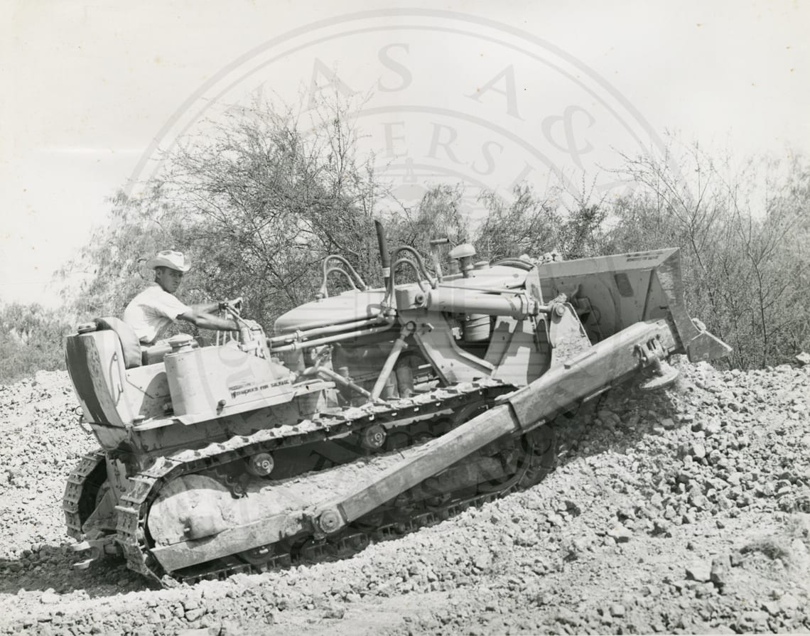 Charles Tucker, farm superintendent, at the controls of the bulldozer.