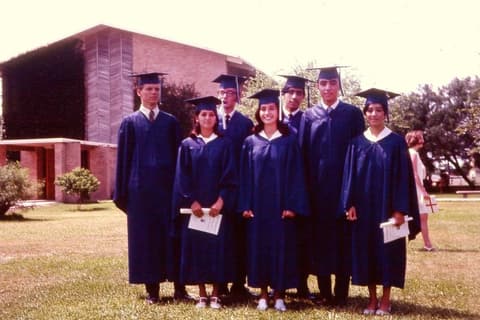 Some of the Class of 1969 in caps and gowns on graduation day, the classroom building behind them.