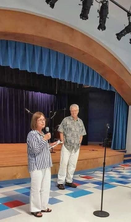 Laura Alvarado Frischeisen and F. Clark Williams, both Class of 1969, on the auditorium stage during a visit; the post remembers Mrs. Elena Mackay Reisner, who taught generations of students.