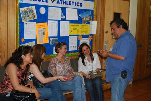 Alumni on the bench by the Eagle Athletics board.
