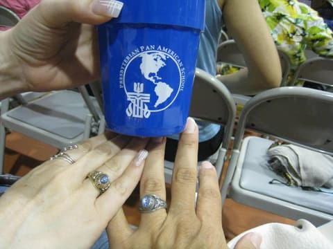 Two original class rings, Adriana Burguete’s (Class of 1982) and Laurie Garcia’s (Class of 1980), with a Centennial cup.