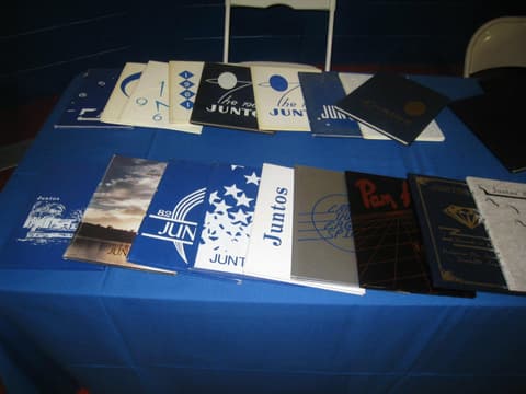 A table of Juntos yearbooks from across the decades at the Centennial; Ernesto Cano, who named the yearbook in 1956, was glad to see them.