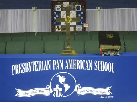 The altar cross and Bible before the school banner, “They shall rise with wings as eagles”, given by the Class of 2008.