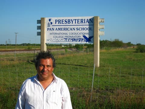 An alumnus beside the old “Presbyterian Pan American School — International Coeducational College Preparatory” road sign, the day after the Centennial.
