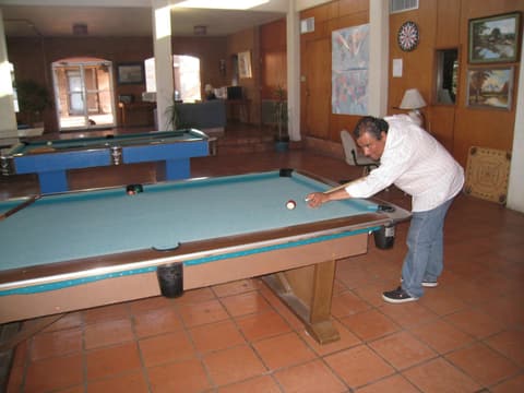 A game of pool in the boys’ dorm living room during the Centennial visit; alumni remember filling the soda machine under Mrs. Leos’s eye.