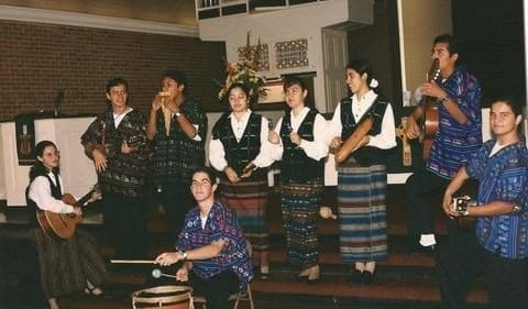 The Andean music group performing in the chapel in woven costumes.