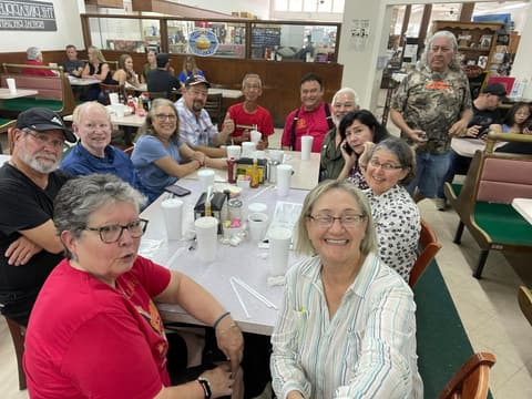 Alumni of the 1970s around a diner table at a reunion.