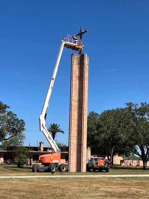 A lift raises the cross to the top of the chapel tower.