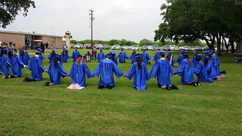 Graduates kneel in a circle on the lawn — a tradition alumni say the Class of 1999 started.