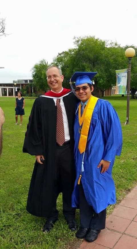 A graduate with a teacher in academic robes after the ceremony.