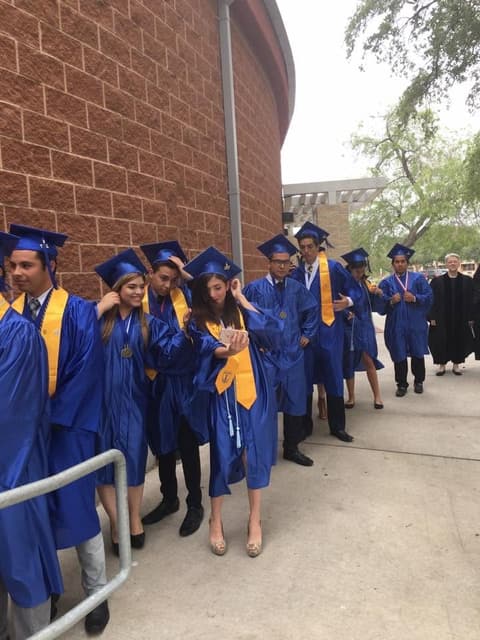 Graduates lining up along the gym wall before the procession.