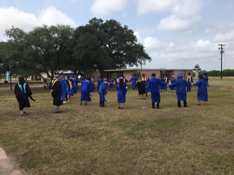 New graduates celebrating on the lawn under the oaks.