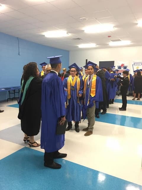 Graduates in blue gowns and gold stoles lining up for the ceremony.