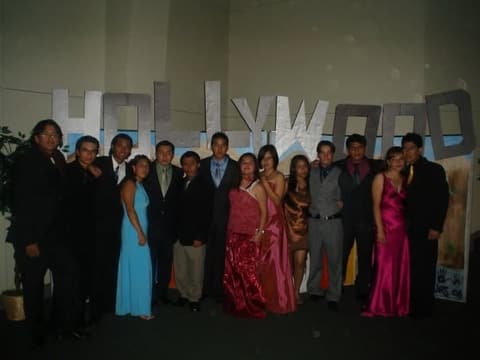 Students dressed for prom in front of a silver ‘Hollywood’ backdrop.
