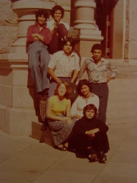 Friends posed on the steps of a stone building on a trip.