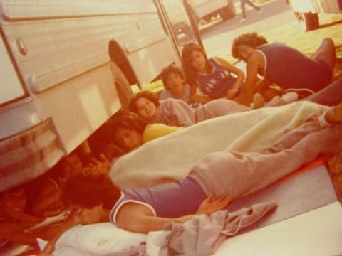 Students asleep on the floor beside the bus during a trip.