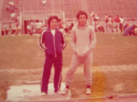 Two boys in warm-up suits at the track before a meet.