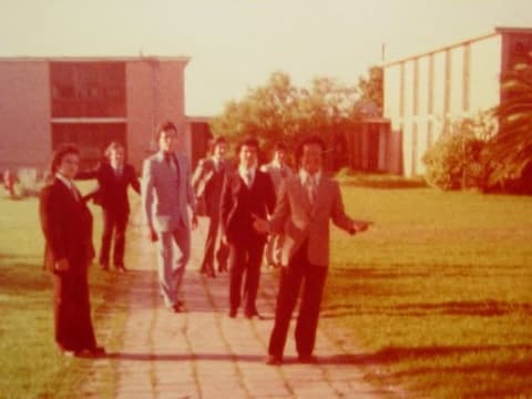 Boys in suits walking to prom night along the campus walkway.