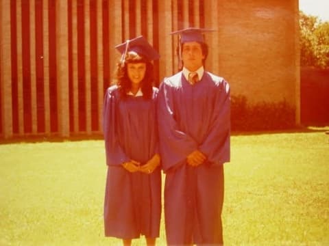 Two members of the Class of 1981 in front of the chapel’s ribbed brick wall.