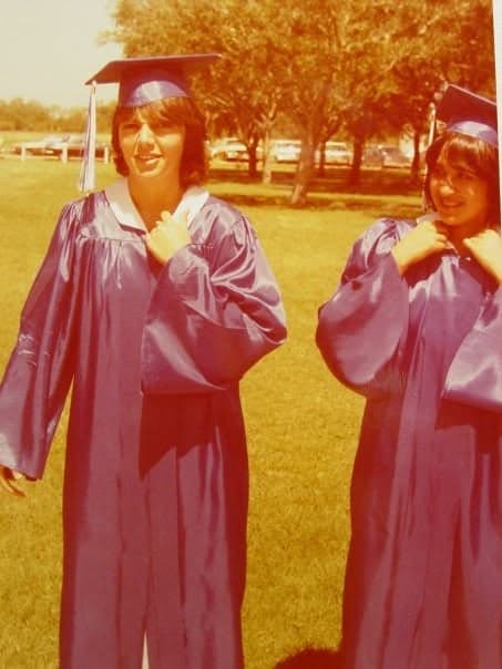 Two members of the Class of 1981 in caps and gowns on the lawn.