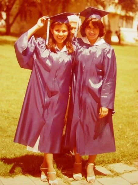 Two graduates in caps and gowns on the lawn.