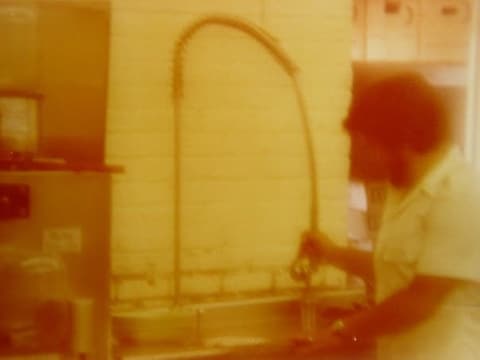 A student at the dish-washing station in the kitchen — the work program every boarder did.