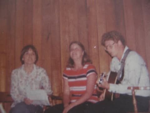 Two students singing along with a classmate on guitar at a Saturday night gathering, 1977.