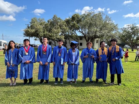 The Class of 2026 in caps and gowns under the oaks, May 16, 2026.