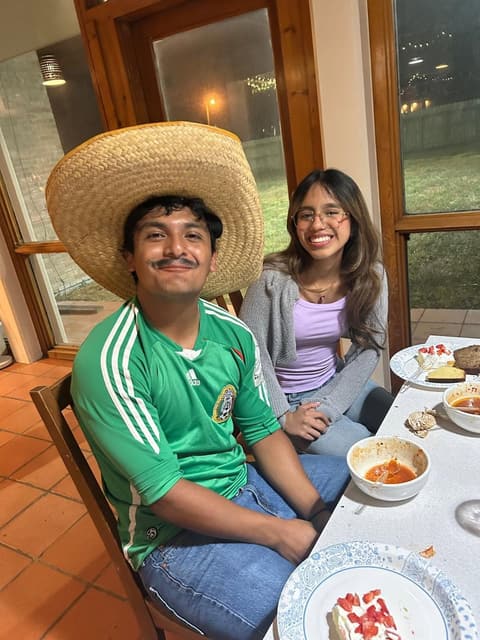 Students at a festive dinner night in the dorm lounge, with sombreros and a Mexican-flag spread, fall 2025.