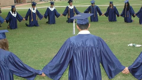 Graduates hold hands in a circle on the lawn after the ceremony, a Pan Am tradition.