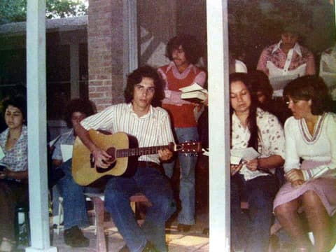 Singing with a guitar on the porch during a gathering, late 1970s.