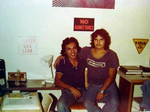 Two roommates under the joke signs on their dorm wall — “No admittance”, “Danger gas leak”.