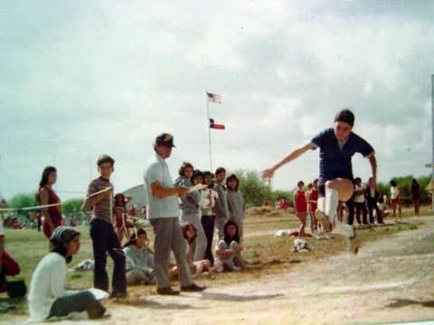 A long jumper in mid-air at a track meet.