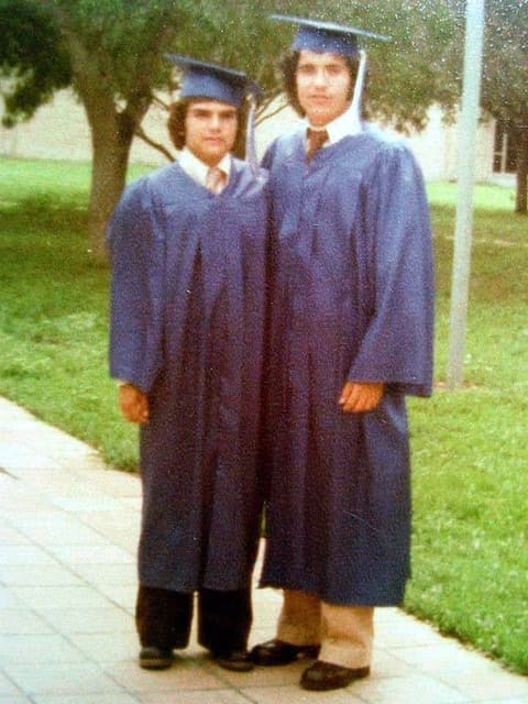 Two graduates in caps and gowns on the walkway, 1978.