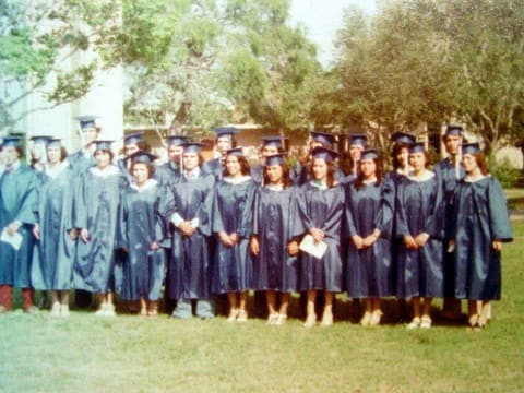 The Class of 1978 in caps and gowns under the trees on graduation day.