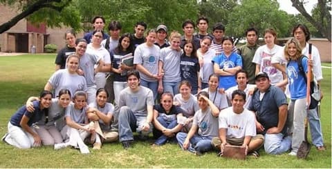 A big group of students in PPAS T-shirts on the lawn by the chapel; alumni in the comments debate when the little trees were planted.