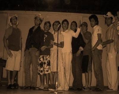 Senior boys in cowboy hats and costumes on stage at a talent show.