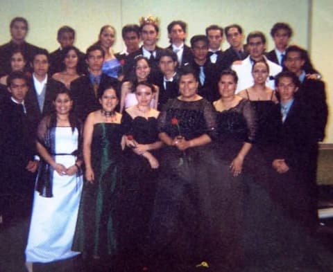 Students in formal wear at a banquet, one of them crowned.