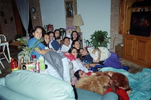 A sleepover: girls piled onto the couch and the floor of a dorm living room.