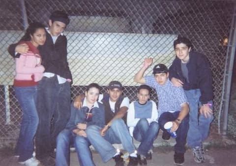 Sophomores hanging out by the chain-link fence at night.