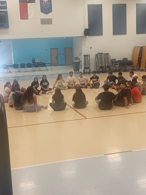 Students sitting in a prayer circle in the gym.