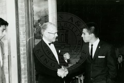 Two men in suits shaking hands.
