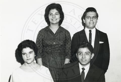 Students - Freshman. Students dressed in formal. A boy and a girl are sitting and another boy and a girl are standing behind them.