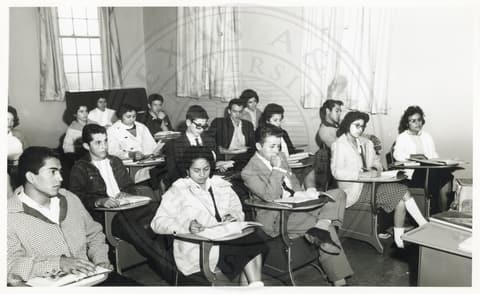 Class. Students sitting in a class with their books opened on their respective desks.